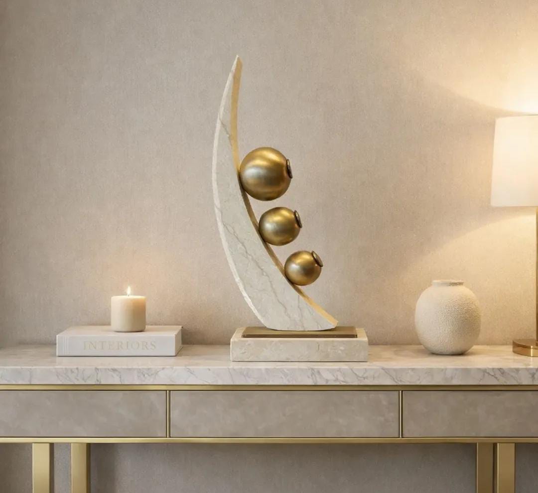 Modern abstract tabletop sculpture featuring gold-toned spheres and a curved design